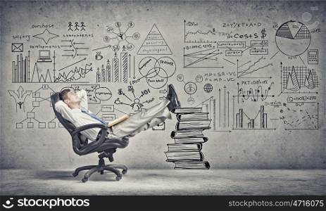 Advantage of education and books reading. Young handsome businessman sitting in chair with his legs on pile of books