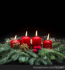 Advent decoration four red burning candles and christmas tree branches on black background