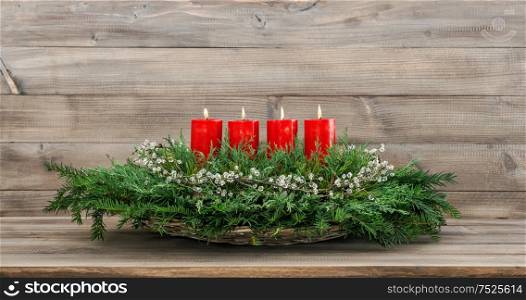 Advent decoration. Four red burning candles, ornaments and christmas tree branches