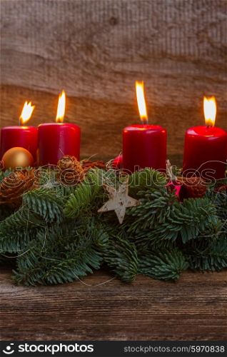 advent wreath with burning candles . Evergreen fir tree advent garland with burning candles on wooden background