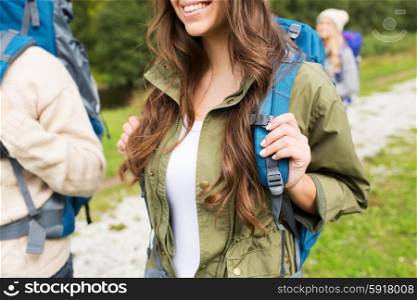 adventure, travel, tourism, hike and people concept - close up of happy woman and her friends hikers with backpacks walking on hiking trail