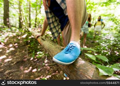 adventure, travel, tourism, hike and people concept - close up of man climbing over fallen tree trunk in woods