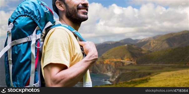 adventure, travel, tourism, hike and people concept - close up of smiling man with backpack over bixby creek bridge on big sur coast of california background. close up of man with backpack on big sur coast. close up of man with backpack on big sur coast