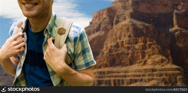 adventure, travel, tourism, hike and people concept - close up of smiling young man with backpack over grand canyon national park background. close up of man with backpack over grand canyon. close up of man with backpack over grand canyon