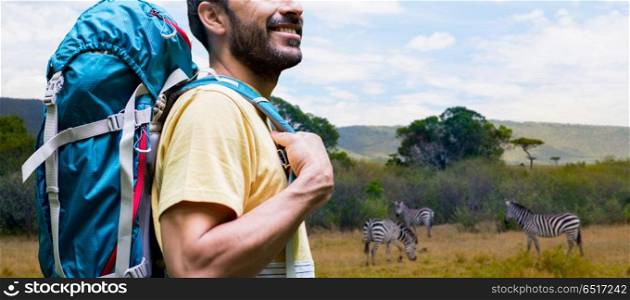 adventure, travel, tourism, hike and people concept - close up of smiling man with backpack over zebras in african savannah background. close up of man with backpack over savannah. close up of man with backpack over savannah