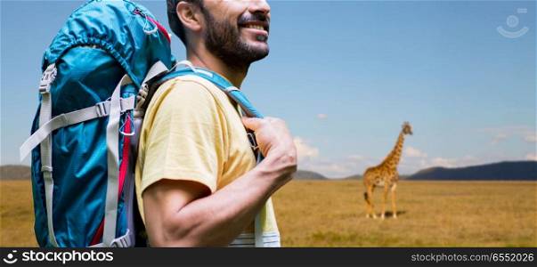 adventure, travel, tourism, hike and people concept - close up of smiling man with backpack over giraffe in african savannah background. close up of man with backpack over savannah. close up of man with backpack over savannah