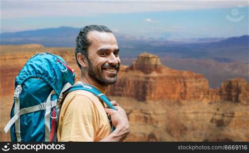 adventure, travel, tourism, hike and people concept - close up of smiling man with backpack over grand canyon national park background. close up of man with backpack over grand canyon. close up of man with backpack over grand canyon