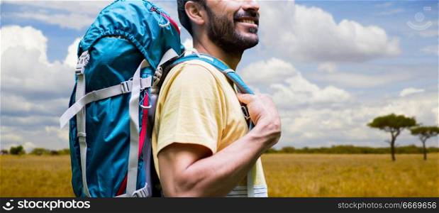 adventure, travel, tourism, hike and people concept - close up of smiling man with backpack over african savannah background. close up of man with backpack over savannah. close up of man with backpack over savannah
