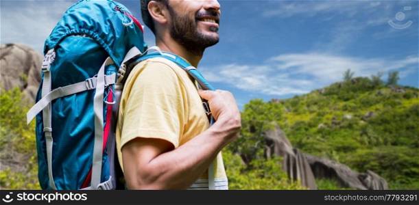 adventure, travel, tourism, hike and people concept - close up of smiling man with backpack over background of seychelles island. close up of man with backpack over seychelles