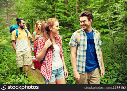 adventure, travel, tourism, hike and people concept - group of smiling friends walking with backpacks in woods