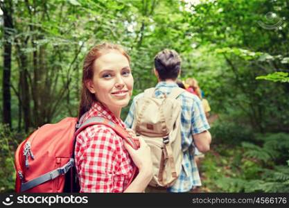 adventure, travel, tourism, hike and people concept - group of smiling friends walking with backpacks in woods