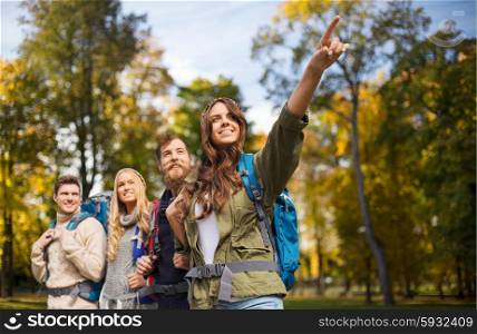 adventure, travel, tourism, hike and people concept - group of smiling friends walking with backpacks over natural background