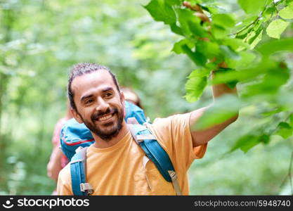 adventure, travel, tourism, hike and people concept - group of smiling friends walking with backpacks in woods