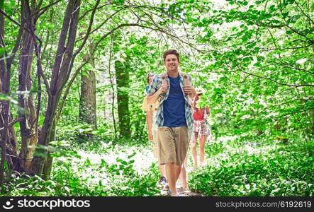 adventure, travel, tourism, hike and people concept - group of smiling friends walking with backpacks in woods