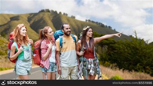 adventure, travel, tourism, hike and people concept - group of smiling friends with backpacks pointing finger over big sur coast of california hills background. group of friends with backpacks on big sur hills. group of friends with backpacks on big sur hills