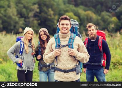 adventure, travel, tourism, hike and people concept - group of smiling friends standing with backpacks
