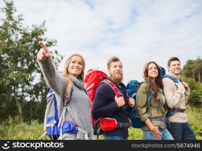 adventure, travel, tourism, hike and people concept - group of smiling friends walking with backpacks