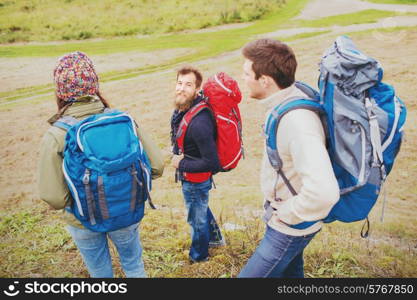 adventure, travel, tourism, hike and people concept - group of smiling friends with backpacks outdoors