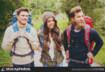 adventure, travel, tourism, hike and people concept - group of smiling friends with backpacks outdoors