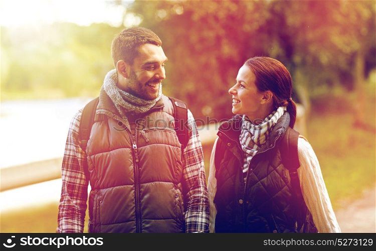 adventure, travel, tourism, hike and people concept - happy family couple walking with backpacks in woods. happy family walking with backpacks in woods