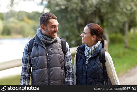adventure, travel, tourism, hike and people concept - happy family couple walking with backpacks in woods