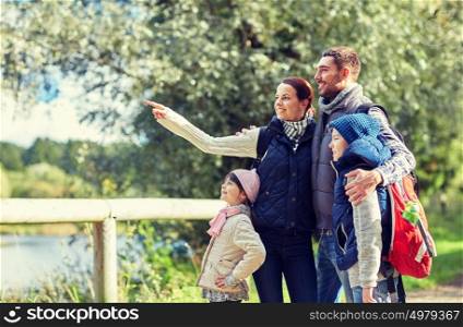 adventure, travel, tourism, hike and people concept - happy family walking with backpacks in woods. happy family with backpacks hiking