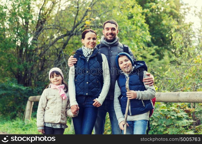 adventure, travel, tourism, hike and people concept - happy family walking with backpacks in woods. happy family with backpacks hiking