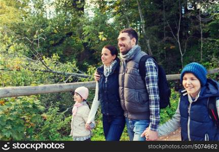 adventure, travel, tourism, hike and people concept - happy family walking with backpacks in woods. happy family with backpacks hiking in woods