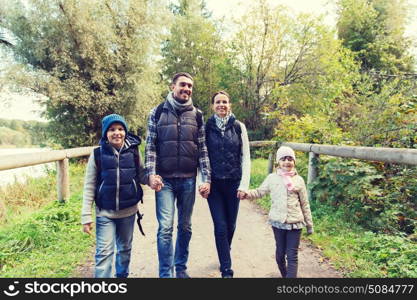 adventure, travel, tourism, hike and people concept - happy family walking with backpacks in woods. happy family with backpacks hiking in woods. happy family with backpacks hiking in woods