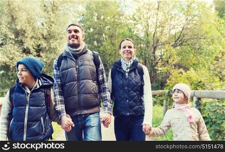 adventure, travel, tourism, hike and people concept - happy family walking with backpacks in woods. happy family with backpacks hiking in woods