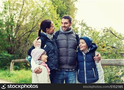 adventure, travel, tourism, hike and people concept - happy family walking with backpacks in woods. happy family with backpacks hiking