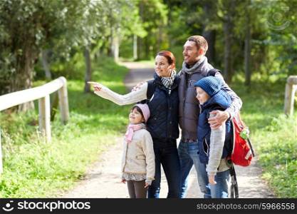 adventure, travel, tourism, hike and people concept - happy family walking with backpacks in woods