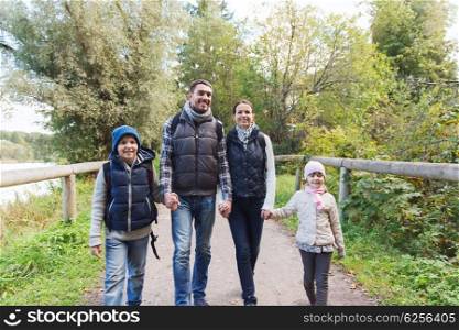 adventure, travel, tourism, hike and people concept - happy family walking with backpacks in woods