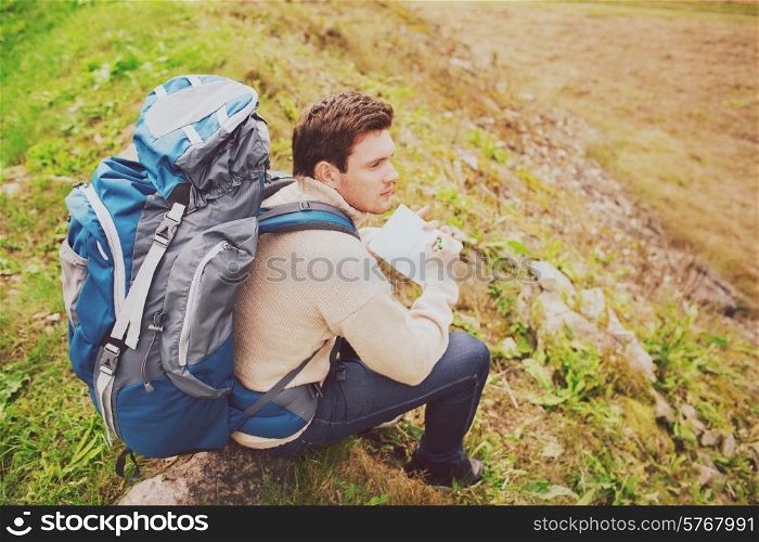 adventure, travel, tourism, hike and people concept - man with backpack sitting on ground from back