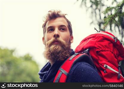 adventure, travel, tourism, hike and people concept - man with beard and red backpack hiking