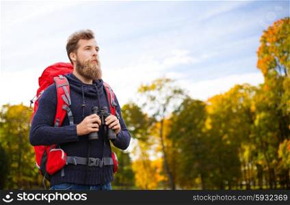 adventure, travel, tourism, hike and people concept - man with red backpack and binocular over natural background