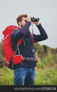 adventure, travel, tourism, hike and people concept - man with red backpack and binocular outdoors