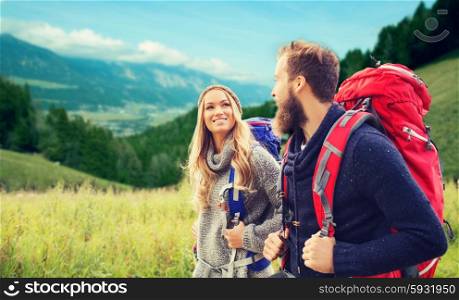 adventure, travel, tourism, hike and people concept - smiling couple walking with backpacks over alpine hills background