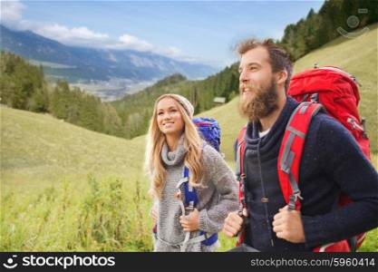 adventure, travel, tourism, hike and people concept - smiling couple walking with backpacks over natural landscape background