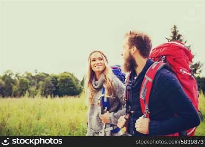 adventure, travel, tourism, hike and people concept - smiling couple walking with backpacks outdoors