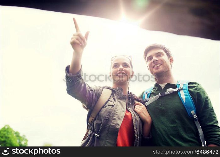adventure, travel, tourism, hike and people concept - smiling couple with backpacks standing at signpost outdoors. smiling couple with backpacks hiking. smiling couple with backpacks hiking