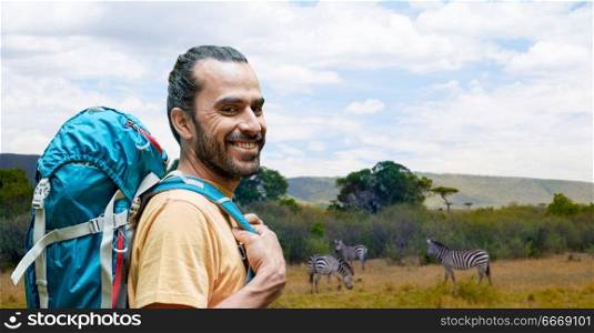 adventure, travel, tourism, hike and people concept - smiling man with backpack over zebras in african savannah background. smiling man with backpack over african savannah. smiling man with backpack over african savannah