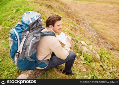 adventure, travel, tourism, hike and people concept - smiling man with backpack sitting on ground