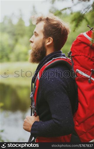 adventure, travel, tourism, hike and people concept - smiling man with beard and red backpack hiking