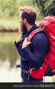 adventure, travel, tourism, hike and people concept - smiling man with beard and red backpack hiking