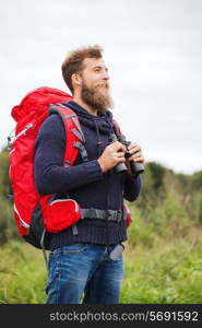 adventure, travel, tourism, hike and people concept - smiling man with red backpack and binocular outdoors