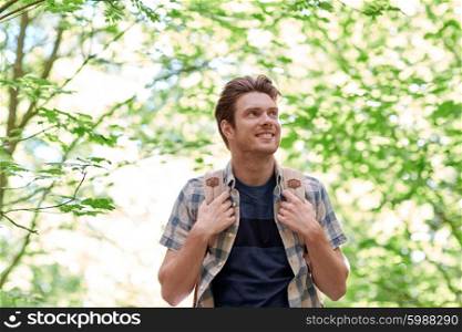 adventure, travel, tourism, hike and people concept - smiling young man with backpack hiking in woods