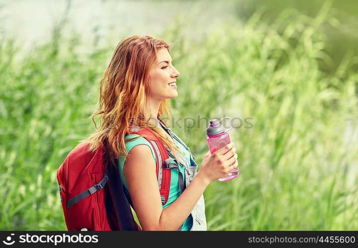 adventure, travel, tourism, hike and people concept - smiling young woman with backpack and bottle of water outdoors