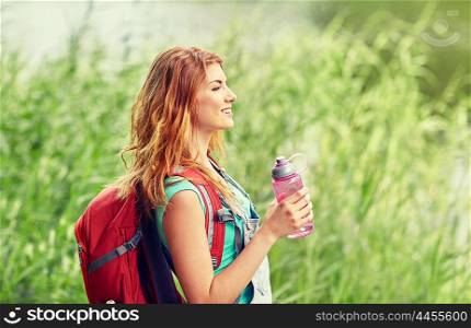adventure, travel, tourism, hike and people concept - smiling young woman with backpack and bottle of water outdoors