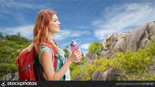 adventure, travel, tourism, hike and people concept - smiling young woman with backpack and bottle of water over background of seychelles island. happy woman with backpack over seychelles island. happy woman with backpack over seychelles island